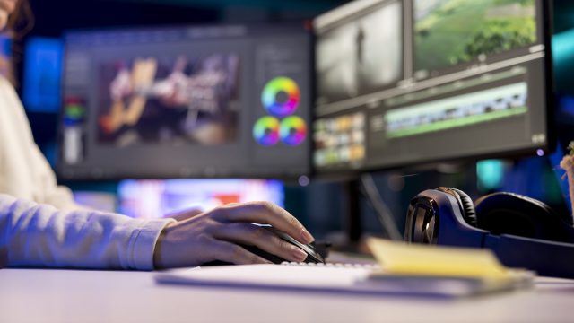 Video editor selecting key frames to use while doing video montage, using specialized software applications. Freelancer using editing tools on computer to cut movie project footage in office, close up